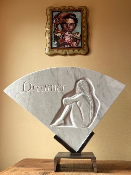 Low relief in Italian marble, The Dreamer is a combination of hand carved letters indicating the word Dreamer and a hand carved image of a woman pondering life.